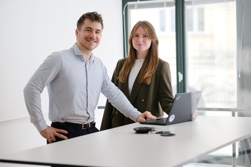 Weiblicher und männlicher Consultant mit Laptop und am Tisch angelehnt.