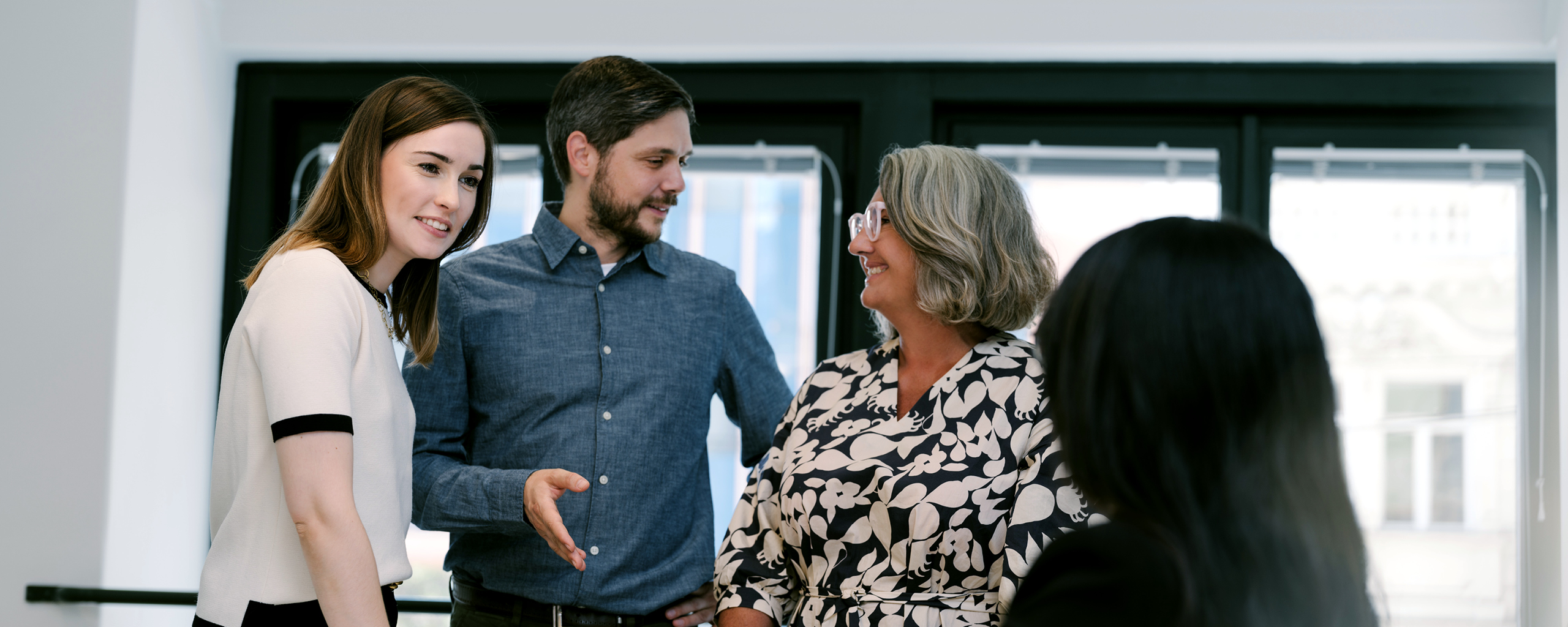 Vier Personen in dem modernen EFS Consulting Büro im Gespräch – symbolisiert Teamarbeit und digitale Zusammenarbeit