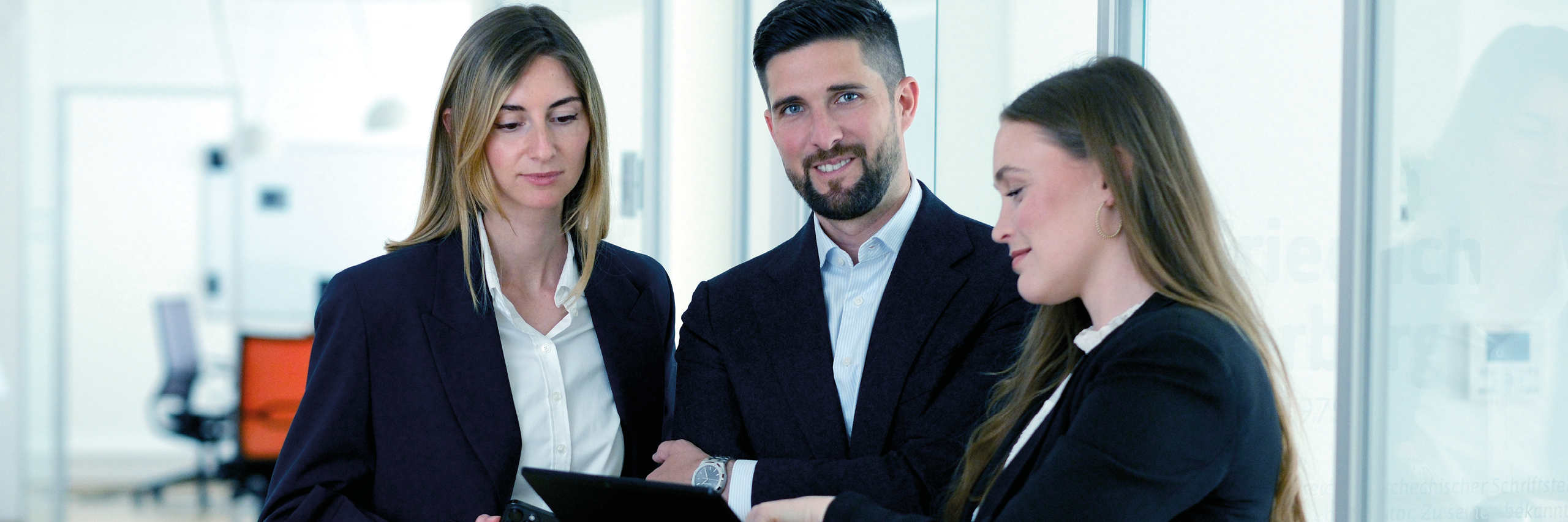 EFS Americas CEO Michael Rinda with two colleagues talking in a light modern office.