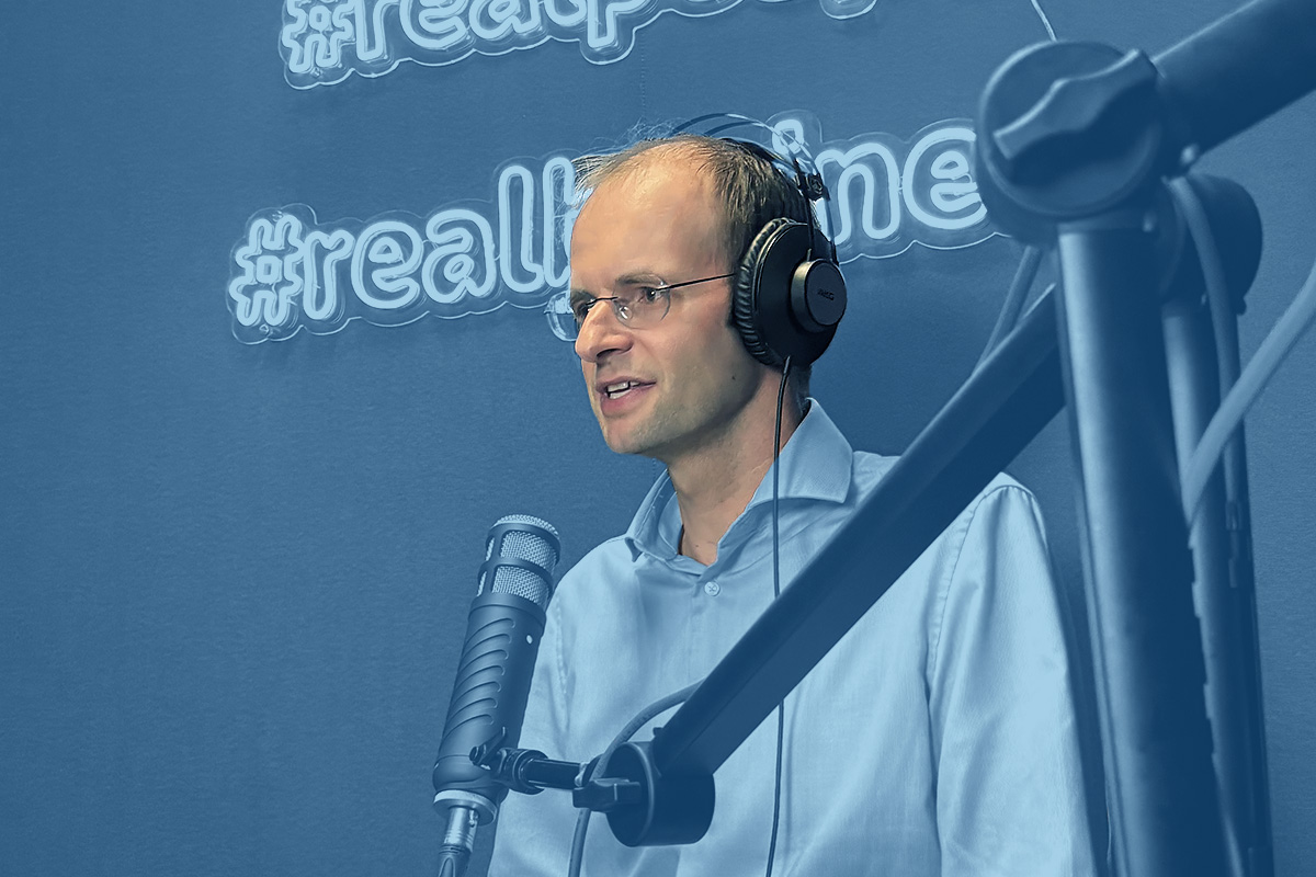 Jochen Schreiber mit Kopfhörer spricht in Mikrofon in Podcast-Raum