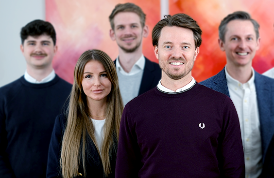 5 Consultants im Office vor einem rot-orangenem Bild im Hintergrund.