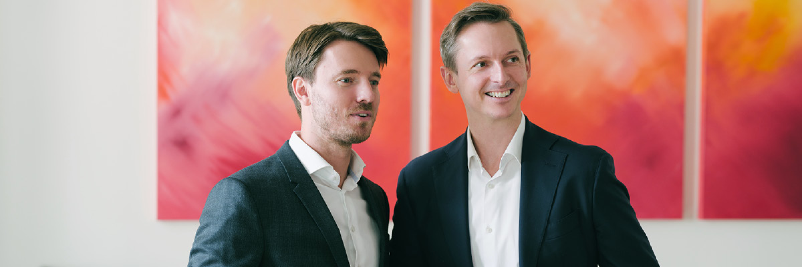 Günther Kolar-Schandlbauer und Fabian Holly im EFS Office hinter einem orange-roten Bild.