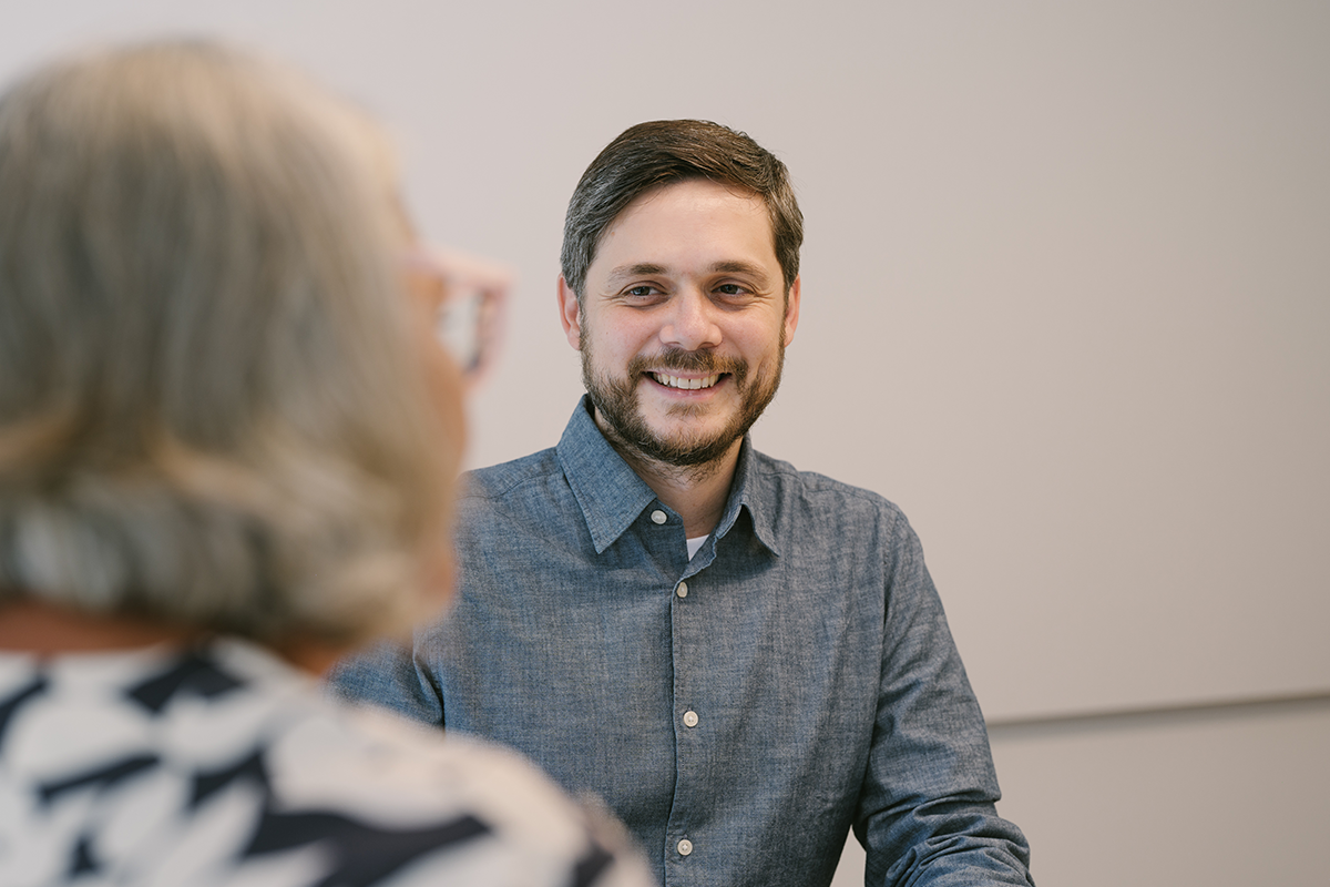 Porträt von Ralph Zlabinger, AI-Experte bei EFS Consulting, lächelnd in einem Gespräch. Im Vordergrund eine unscharfe Gesprächspartnerin.